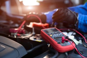 Asian,Technician,Measure,Voltage,Of,Battery,In,The,Car,At